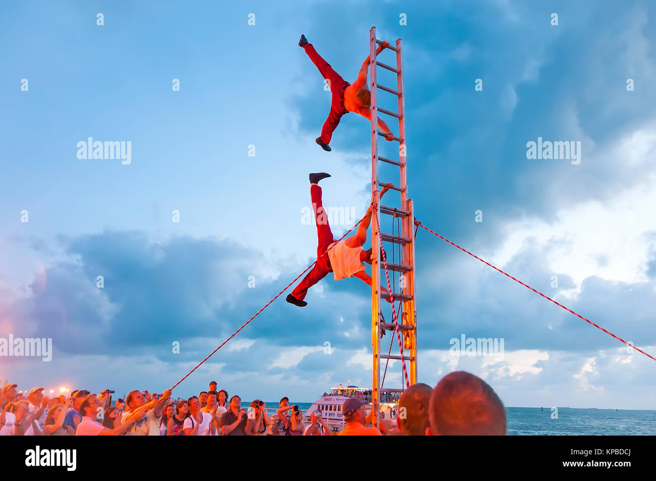 Akrobaten auf Leiter durchführen, vertikaler Ständer bei Sonnenuntergang Feier Key West Florida Stockfoto
