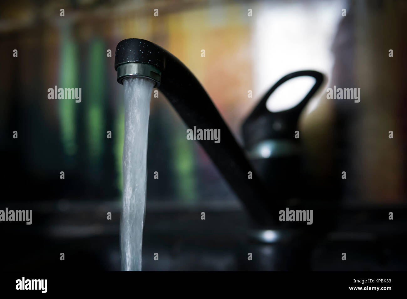 Schlankes, schwarzes und weißes Bild der Wasserhahn tropft, langen Hälsen mit Wassertropfen in Bewegung gestoppt. Ein stilvolles, modernes Design Sanitär. Die schwarze colo Tippen Stockfoto