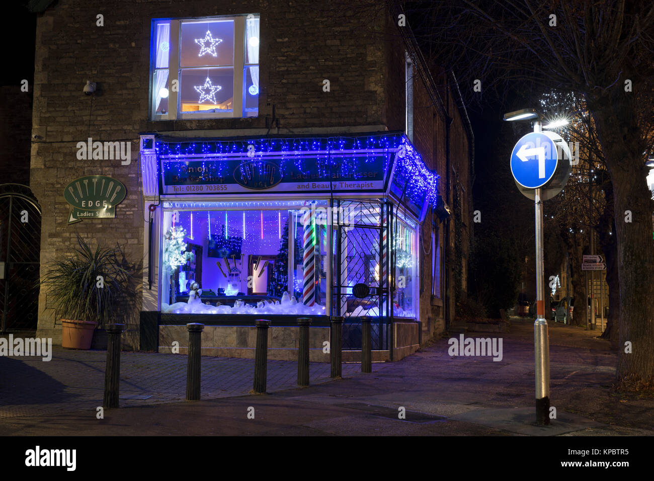 Blue Christmas Lichter und weihnachtliche Dekorationen in der Schneide friseure Schaufenster in Brackley, Northamptonshire, England Stockfoto