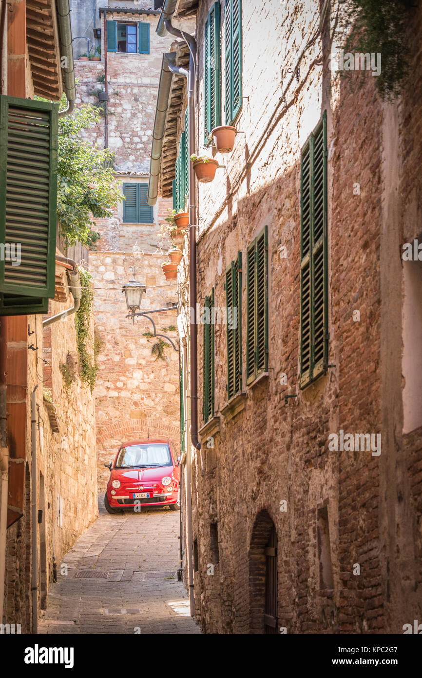 Charakteristische und hübschen Seitenstraße in der Toskana, mit einem roten Fiat 500 Cinquecento in der Ferne geparkt. Stockfoto
