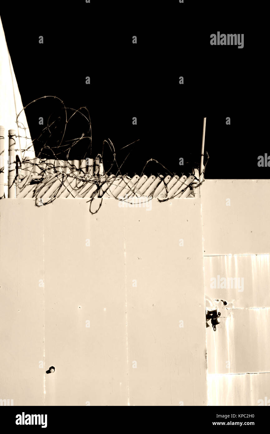 Stacheldraht mit messerscharfen Klingen mit dem Zaun eines Grundstückes. Stockfoto