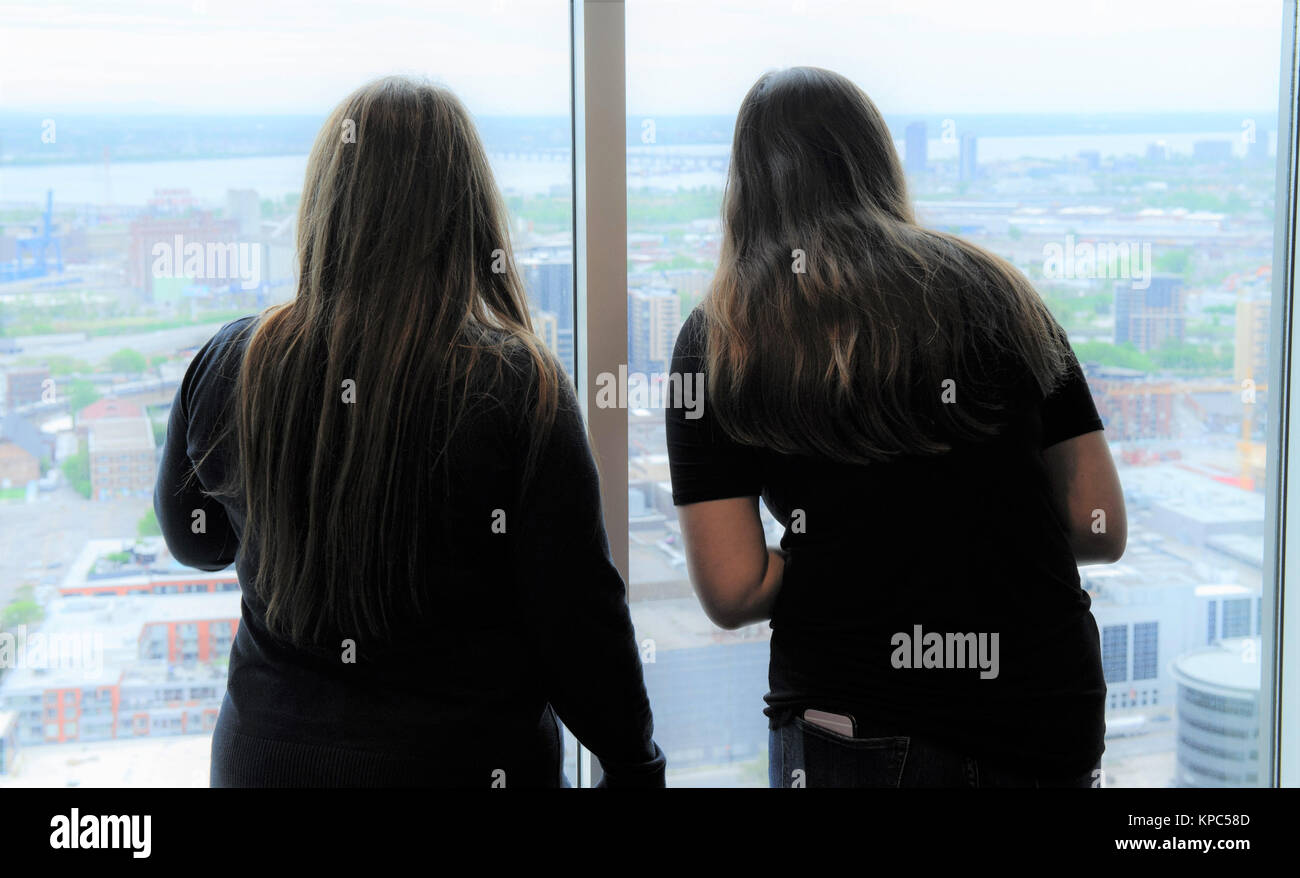 Junge Frauen, die durch das Fenster eines Hochhauses. Stockfoto