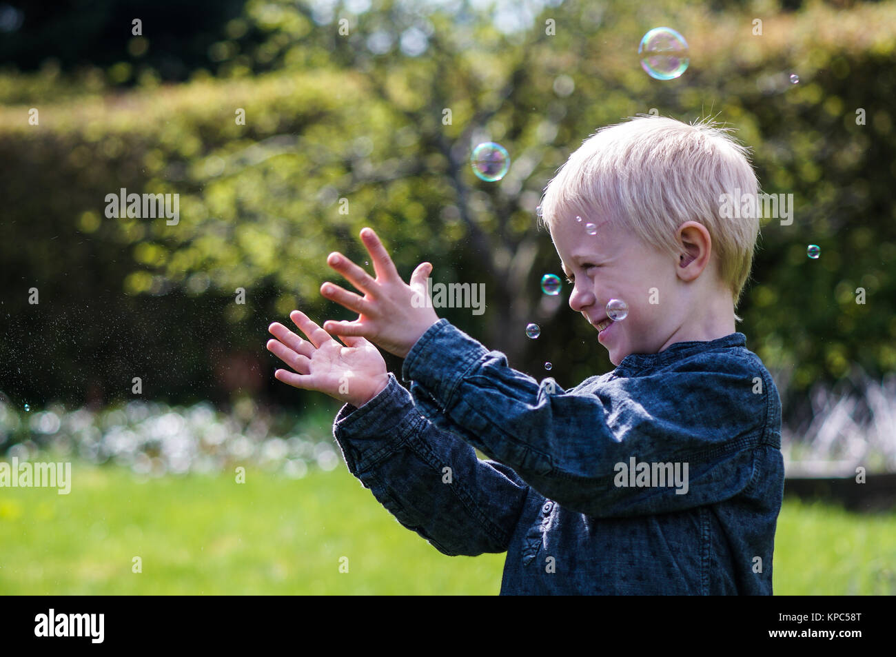 Ein kleiner Junge bläst Seifenblasen im Garten im Sommer Stockfoto