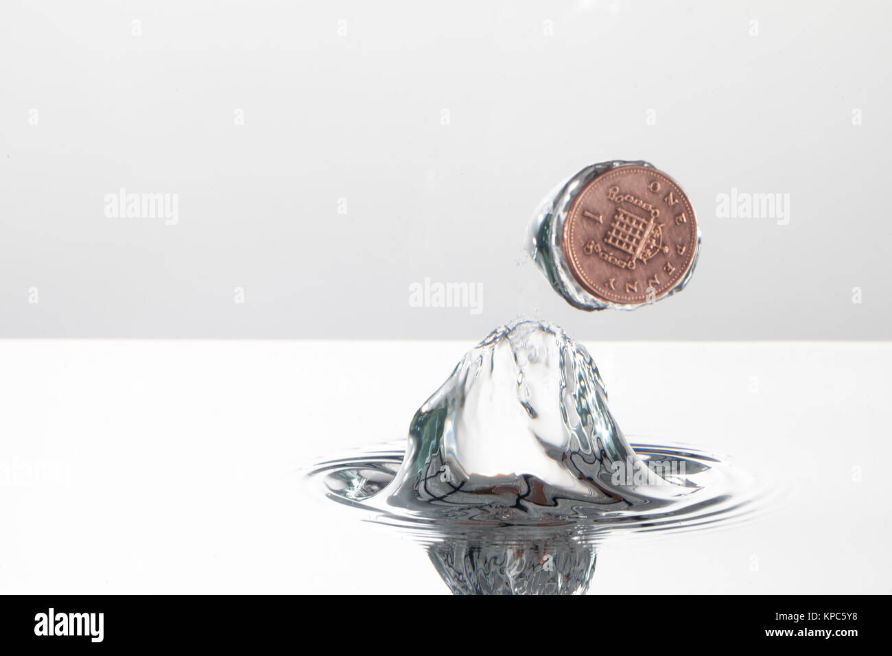 Münze Planschen im Wasser mit hoher Geschwindigkeit Fotografie, auf einem weißen Hintergrund gefangen Stockfoto