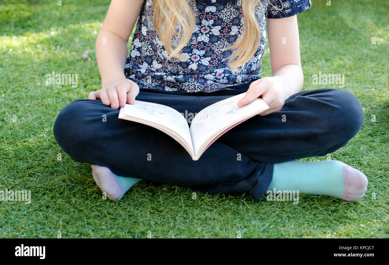 Kleines Mädchen sitzt im Garten lesen Stockfoto