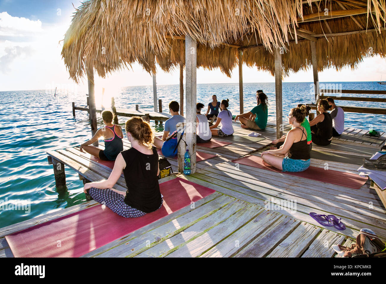 CAYE CAULKER, Belize - 17.12.2015: Yoga am Dock von Caye Caulker Insel am 17.Dezember 2015, Belize. Die Teilnehmer führen Yoga bewegt werden draußen am Meer. Stockfoto