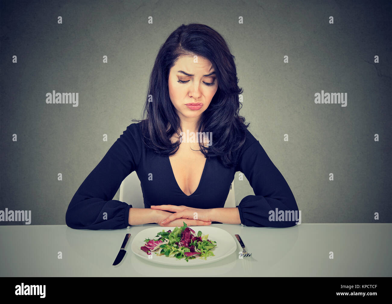 Junge Frau auf Teller mit Salat, mit verzweifelten Ausdruck in Diät. Stockfoto