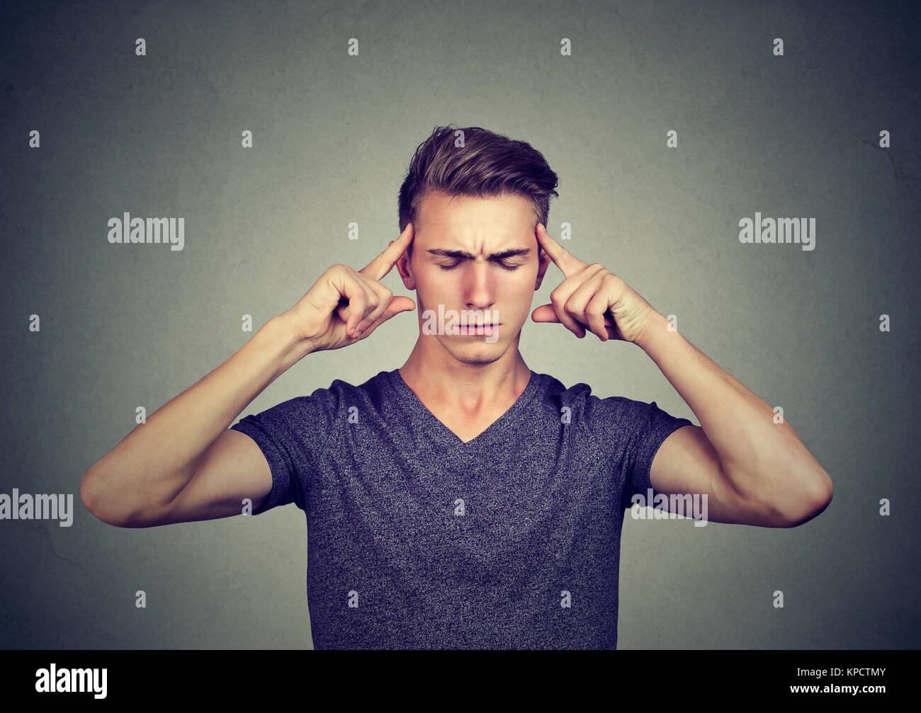 Junge legerer Mann berühren Tempel versuchen, auf etwas, das wichtig halten die Augen geschlossen zu konzentrieren. Stockfoto