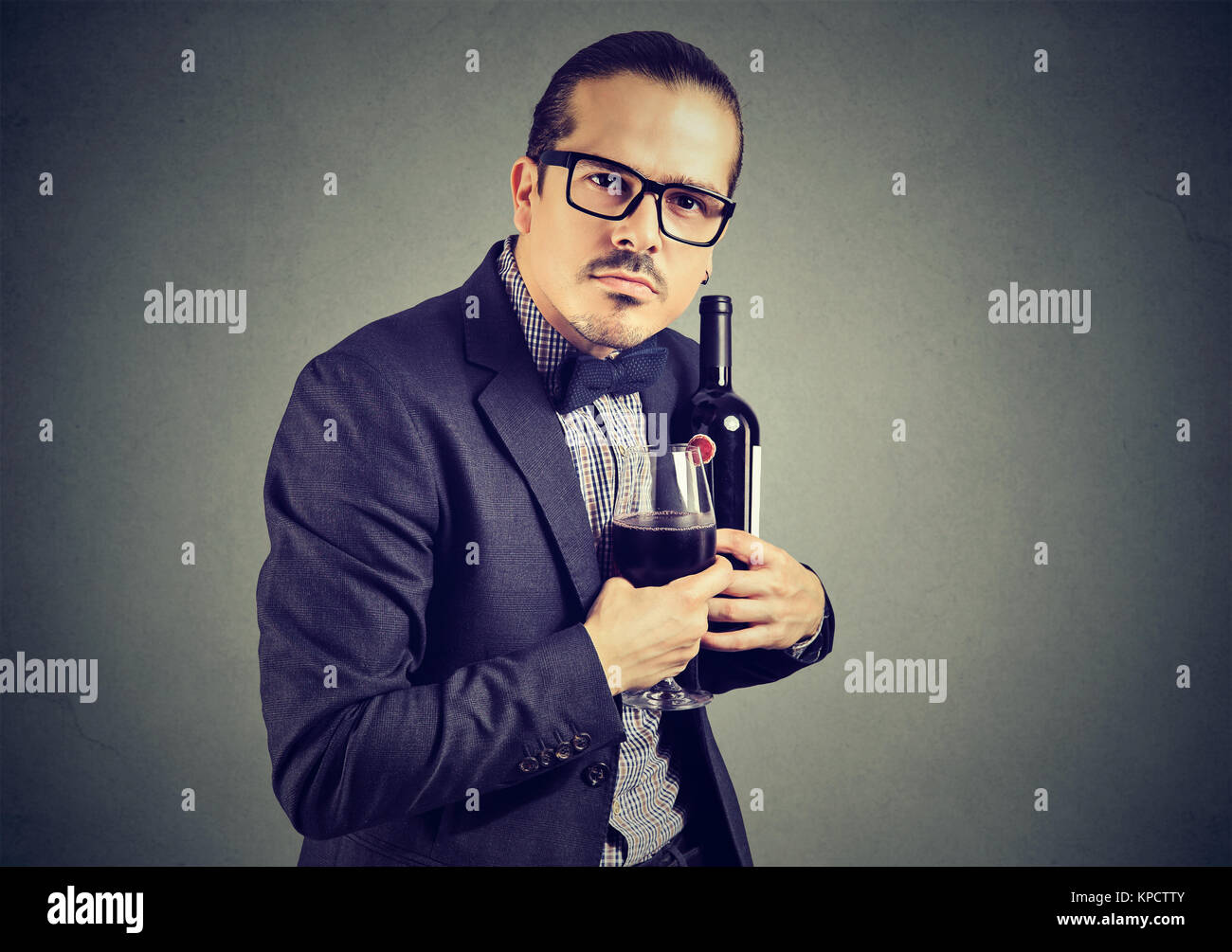 Mann in Anzug und Brille Halten Sie Flasche und Weinglas mit Gefühl der Eigenverantwortung und der Blick auf Kamera. Stockfoto