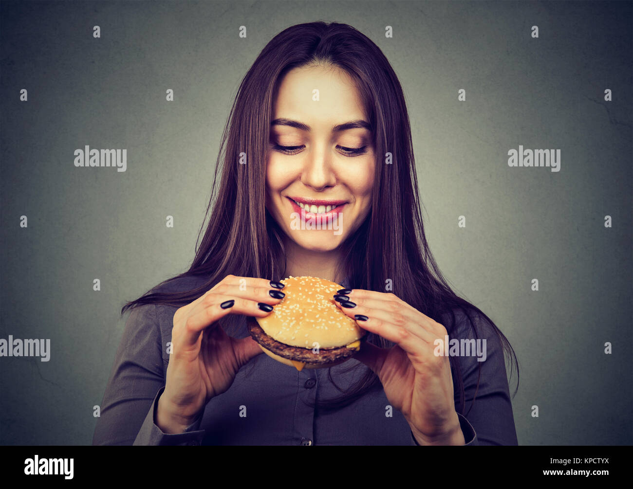 Junge hübsche Frau mit Cheeseburger foretasting köstliche Mahlzeit. Stockfoto