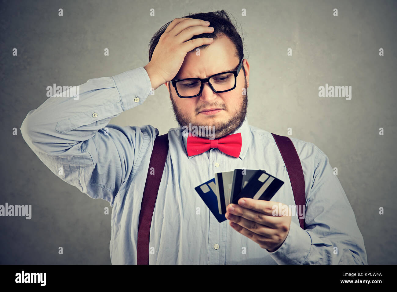 Chubby verwirrte Mann auf der Suche nach Kreditkarten in Hände verzweifelt mit Geld auszugeben. Stockfoto