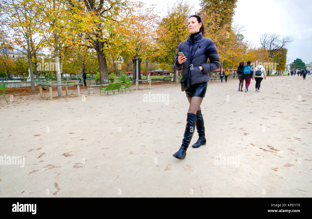 Paris, Frankreich. Jardin des Tuileries im Herbst. Frau gehen mit Ihrem Mobiltelefon Stockfoto