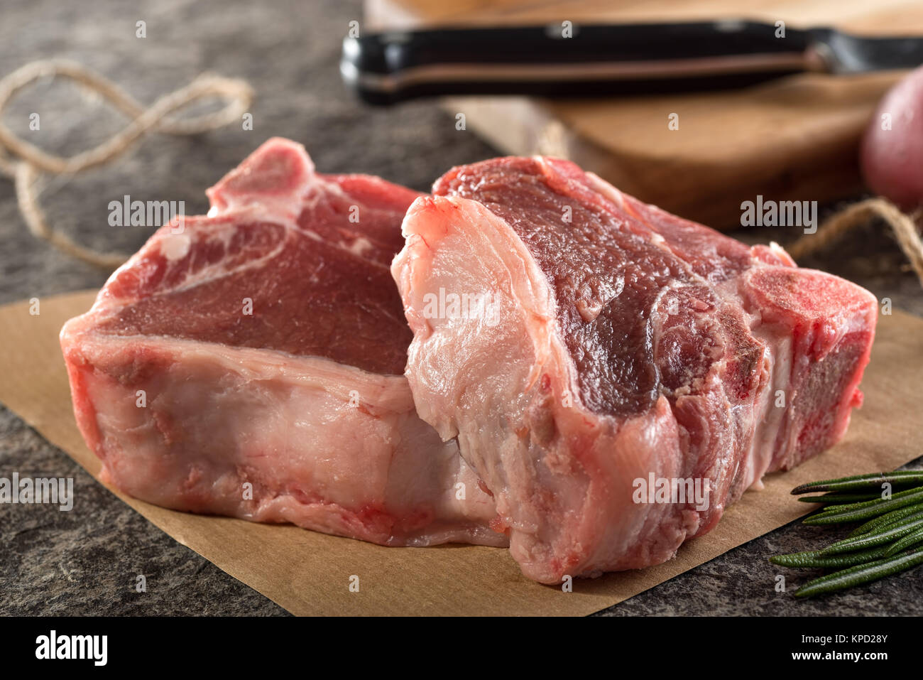 Zwei wunderschön in Marmor raw Lammkoteletts auf Papier mit Metzger Garn und Rosmarin. Stockfoto