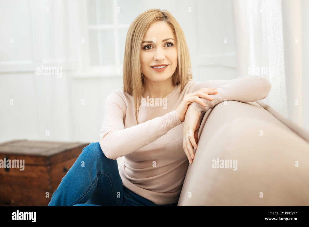 Gut aussehende junge Frau auf dem Sofa sitzt. Stockfoto