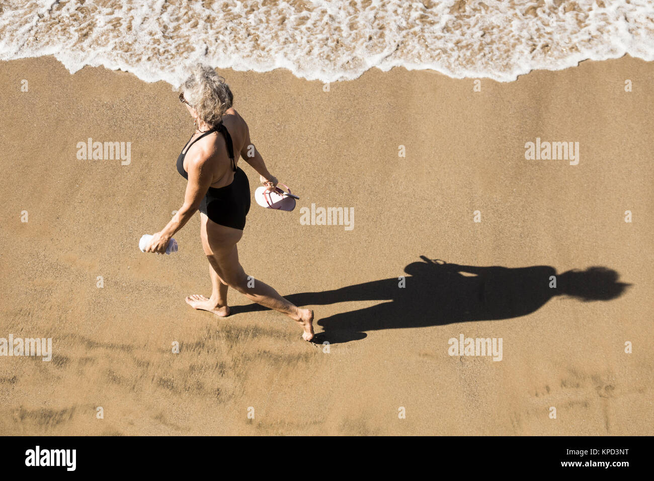 Reife Frau in Badekleidung zu Fuß am Strand in Spanien Stockfoto