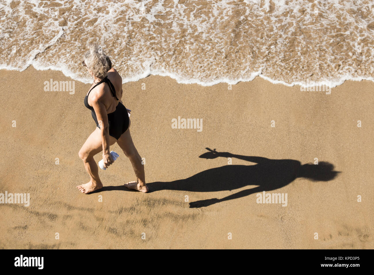 Reife Frau in Badekleidung zu Fuß am Strand in Spanien Stockfoto