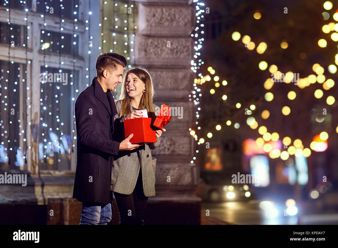 Ein Mann gibt einen Kasten mit einem Geschenk zu seiner Freundin außerhalb. Stockfoto