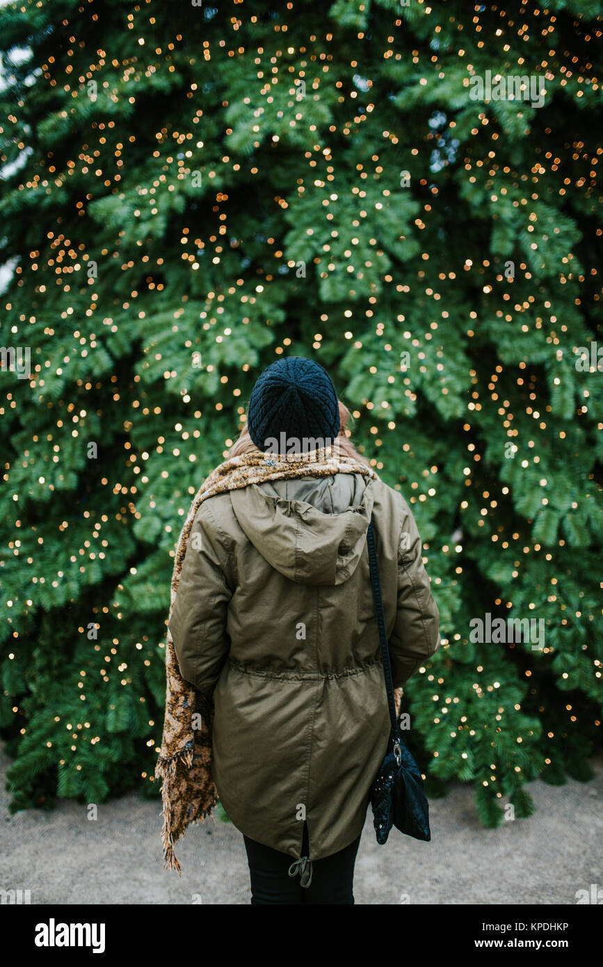 Frau steht vor grossen Weihnachtsbaum Stockfoto