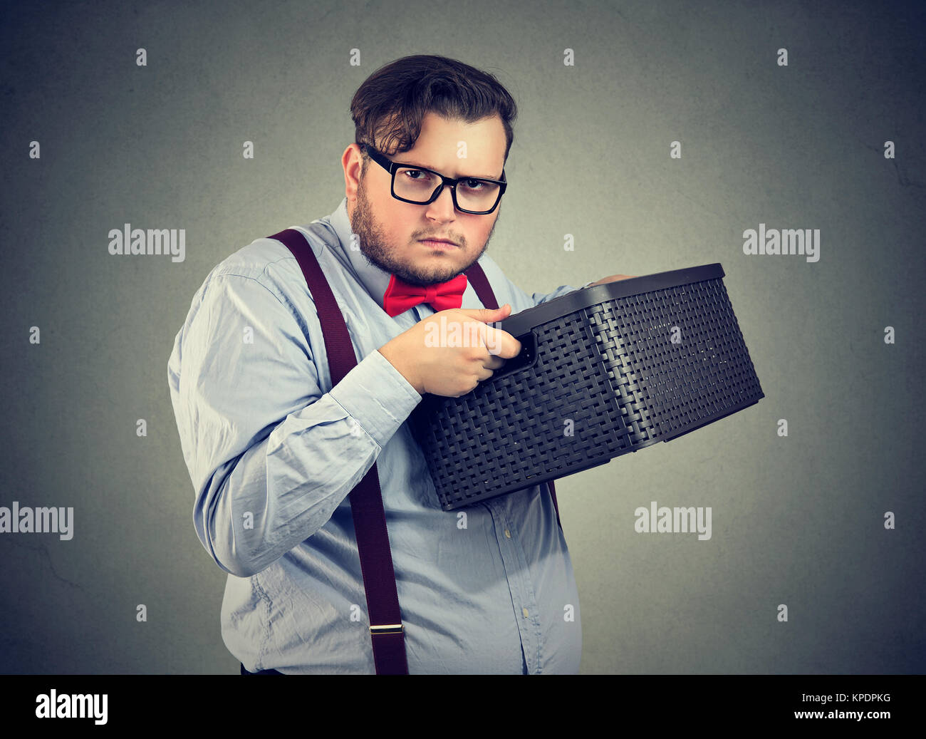 Ungesellig mann Holding Box und Suchen nicht bereit zu teilen, während auf Grau posieren. Stockfoto