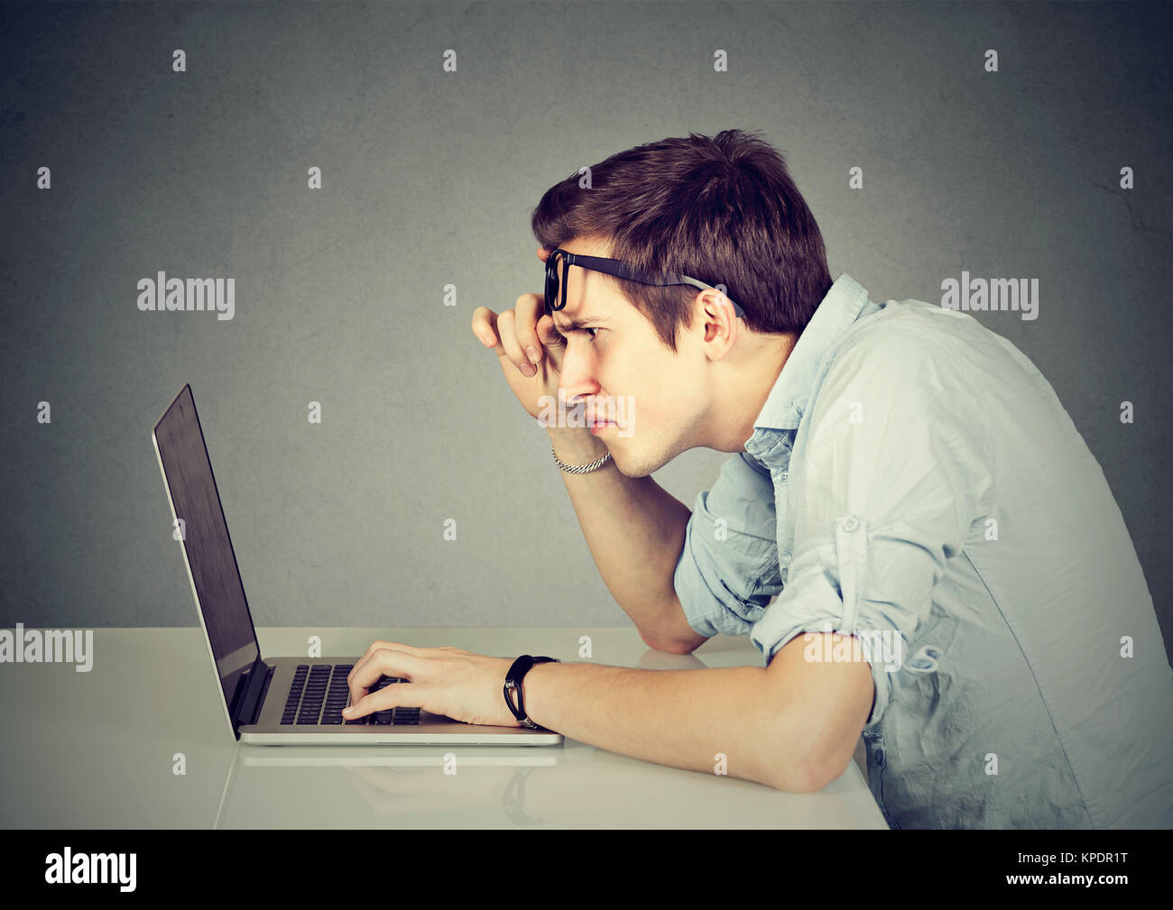 Junger Mann mit Vision Probleme schaut verwirrt, während sie Laptop. Stockfoto