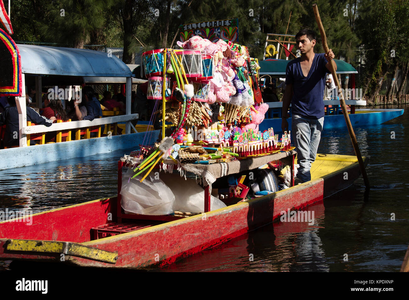 Xochimilco, Mexiko City, Mexiko - 2017: Ein Mann auf einer trajinera (ein lokaler Art des Bootes) verkauft Spielzeug von Menschen in anderen trajineras auf einer Stadt Kanal. Stockfoto