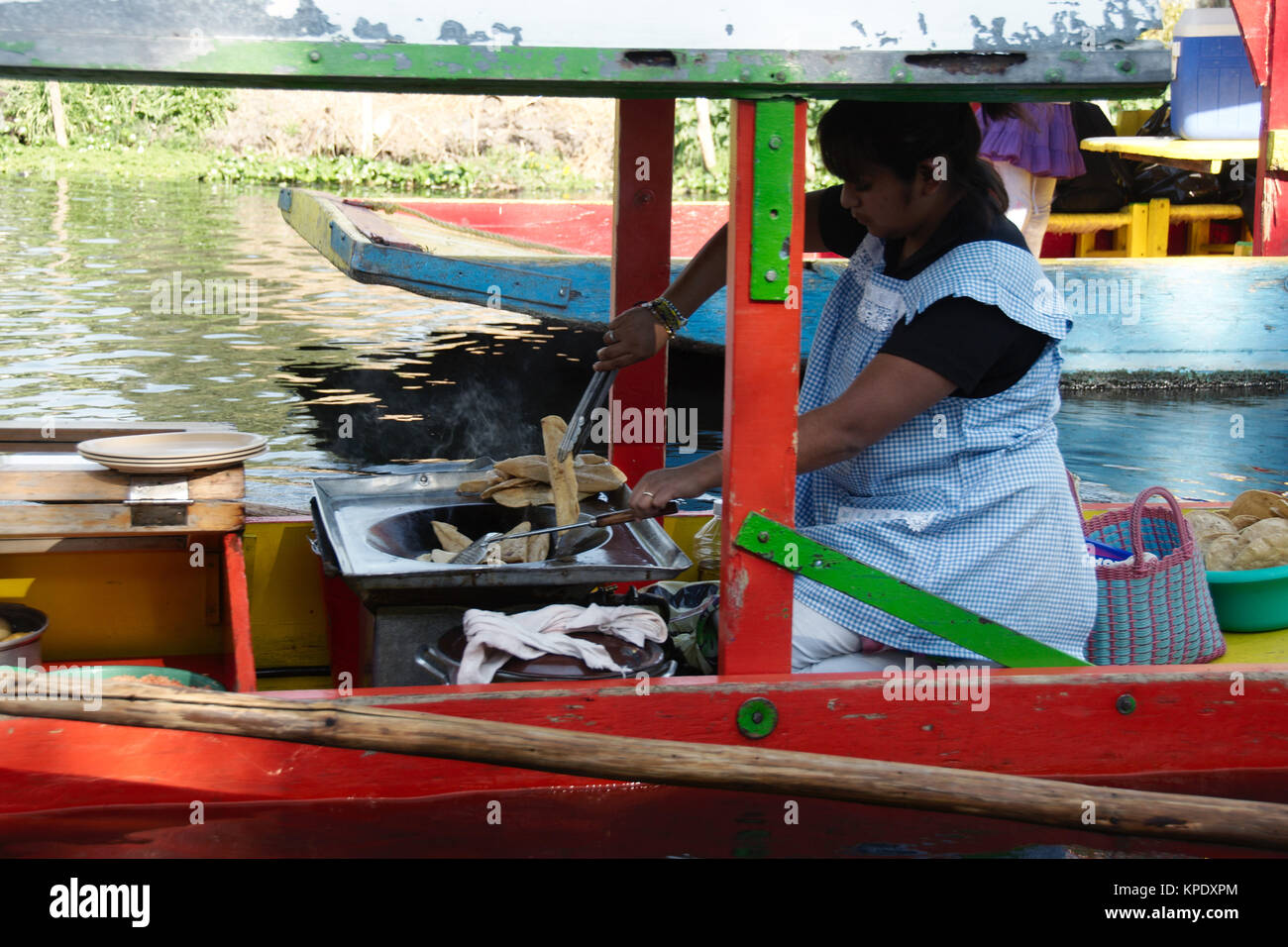 Xochimilco, Mexiko City, Mexiko - 2017: eine Frau auf einer trajinera (ein lokaler Art des Bootes) kocht und verkauft lokales Essen von Menschen in anderen trajineras Stockfoto