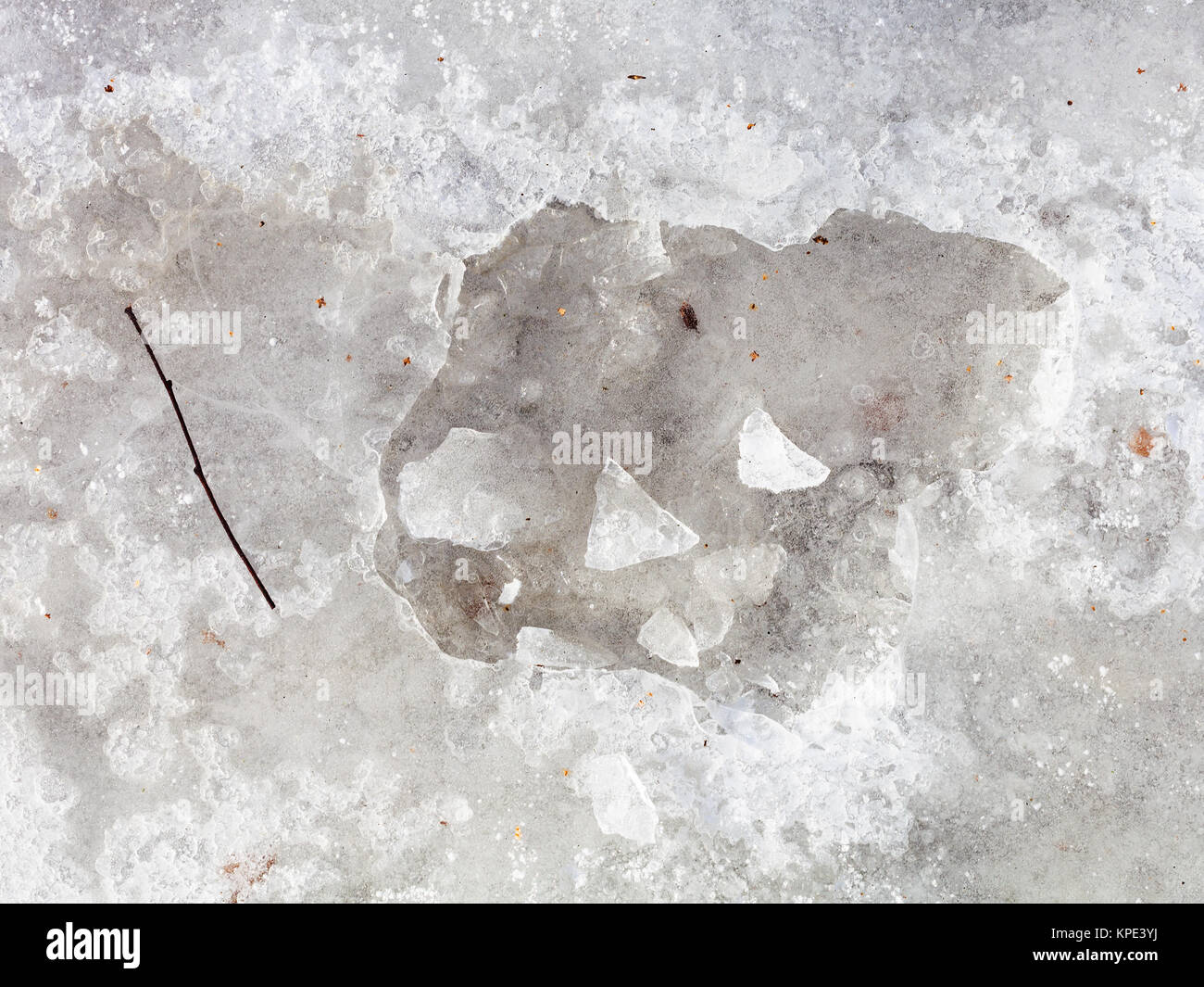 Gebrochene Eiskruste auf gefrorenen Pfütze im Winter Tag Stockfoto