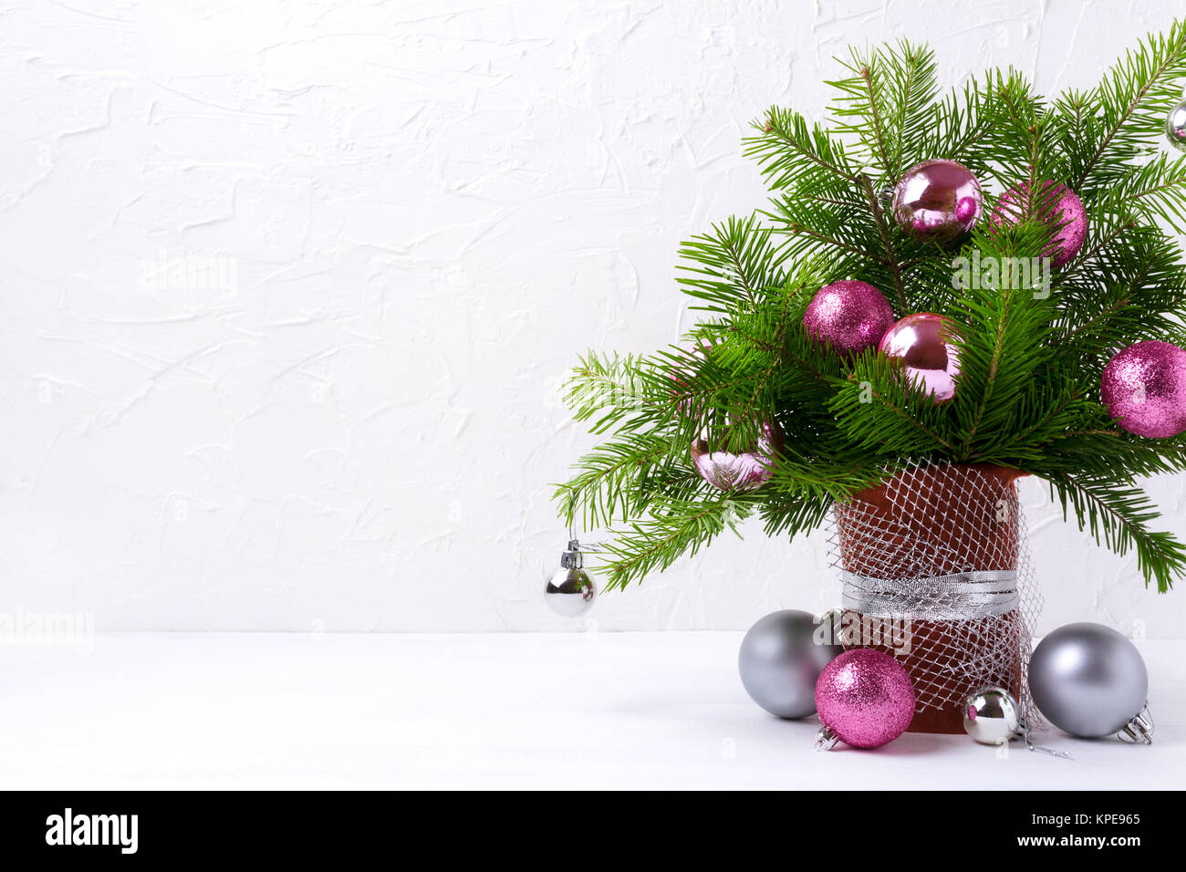 Weihnachten Tabelle Mittelstück mit Tannenzweigen, pink und silber Ornamente in gestaltete Vase auf dem weißen Hintergrund, kopieren Raum Stockfoto