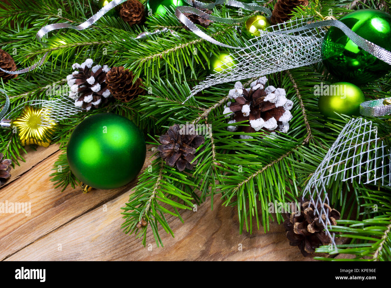 Weihnachten rustikalen Urlaub gruss Hintergrund mit grünen Ornamenten, silberne Band, Schnee dekoriert Pinienzapfen auf dem hölzernen Tisch Stockfoto