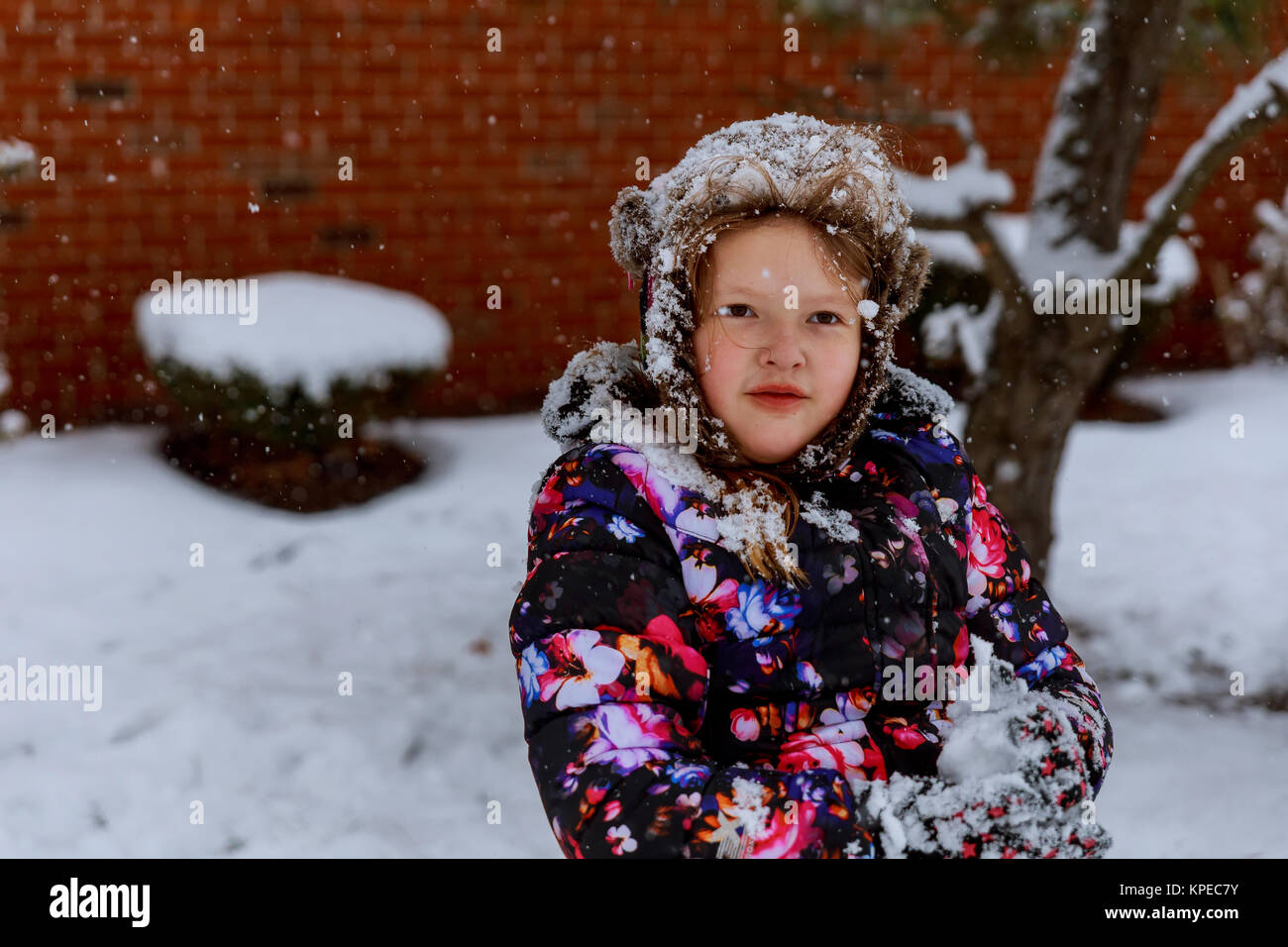 Glückliches lächelndes Mädchen in Rosa wirft snowin die Luft mit Snawflakes fliegen in alle Richtungen Stockfoto