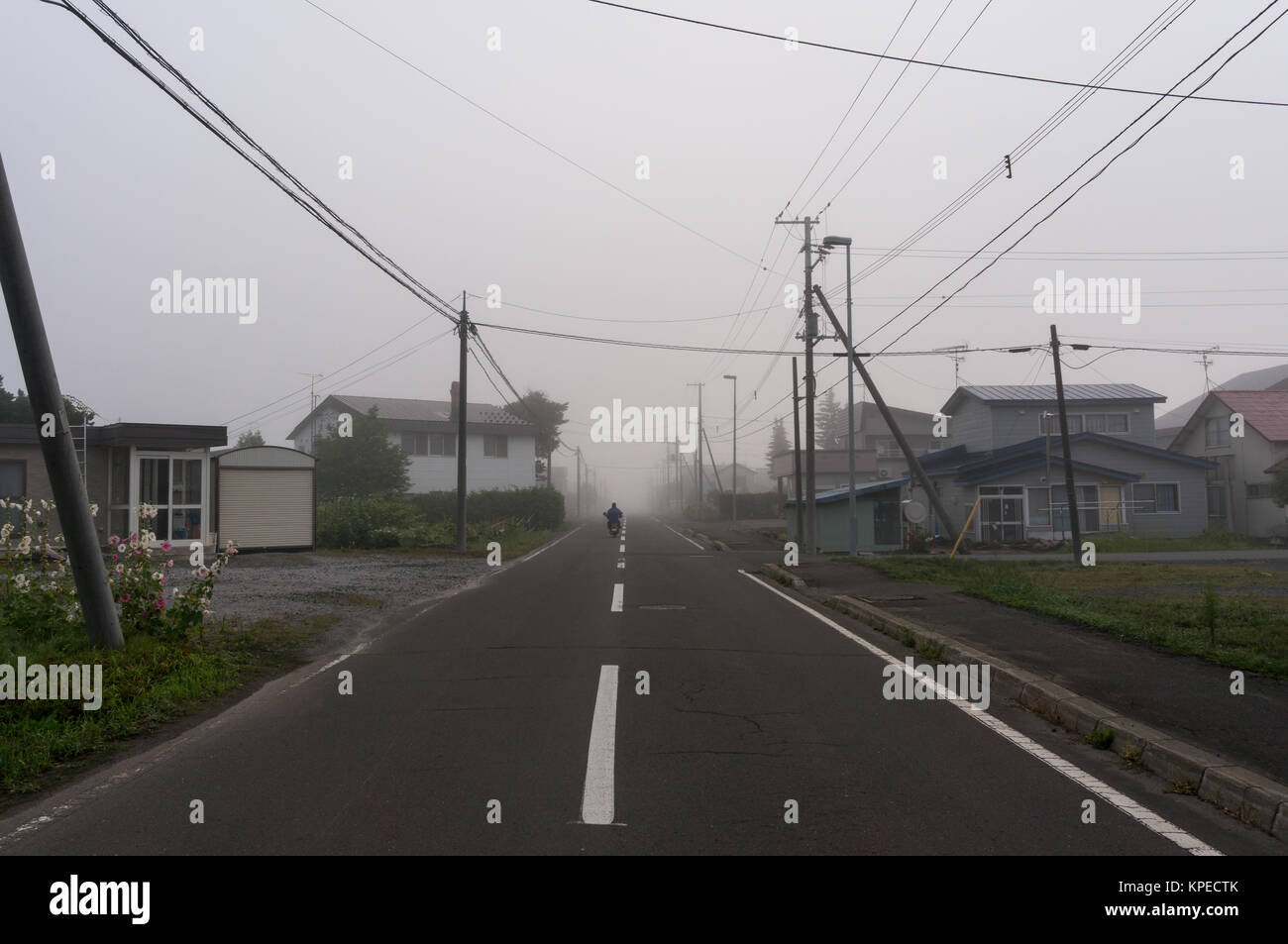 Ein Motorradfahrer, Reiten in der Morgennebel auf dem ruhigen Land japanische Stockfoto