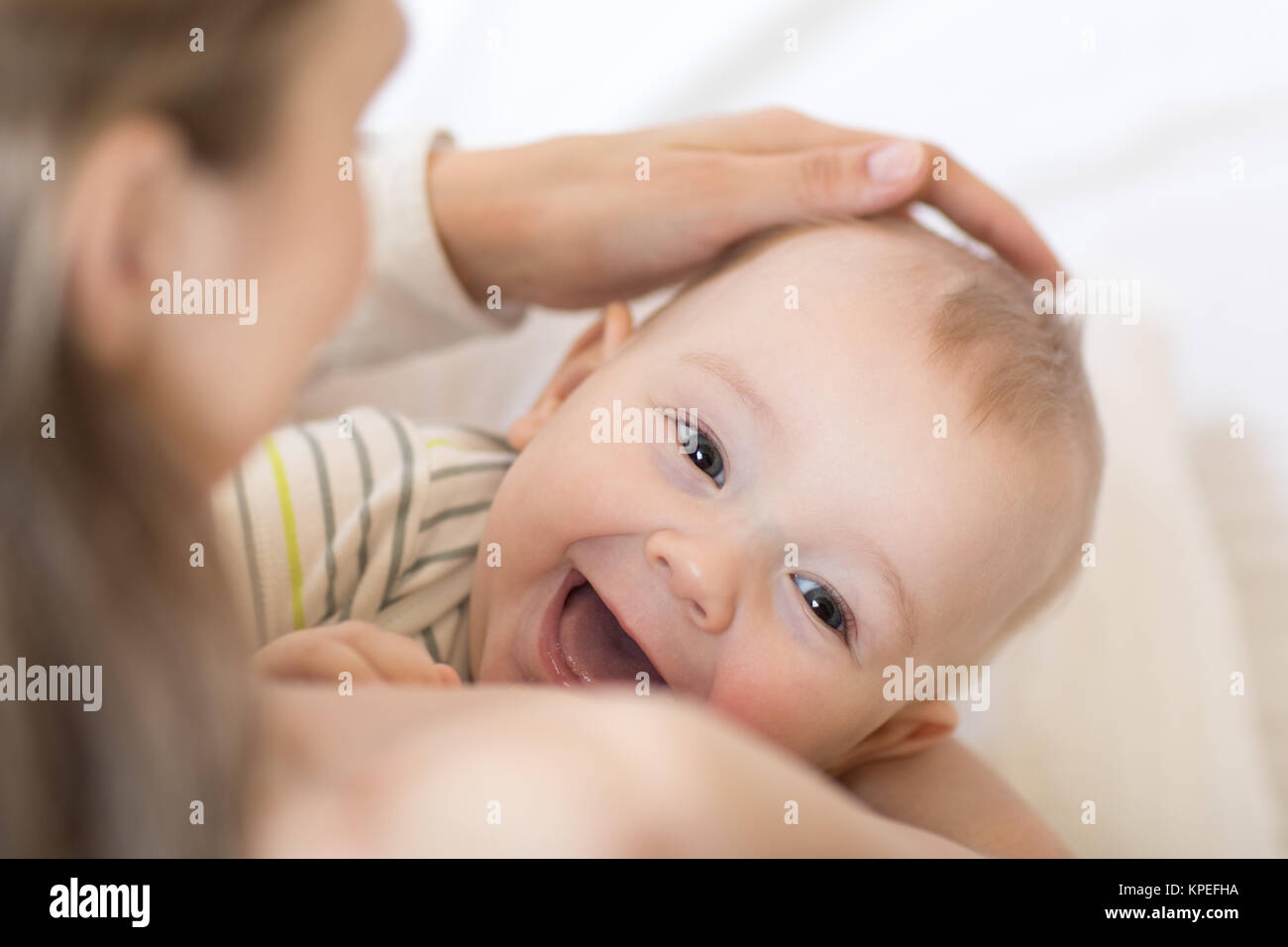 Baby stillen. Die Mutter, die ihr neugeborenes Kind. Kleines Kind lacht und Kamera. Stockfoto