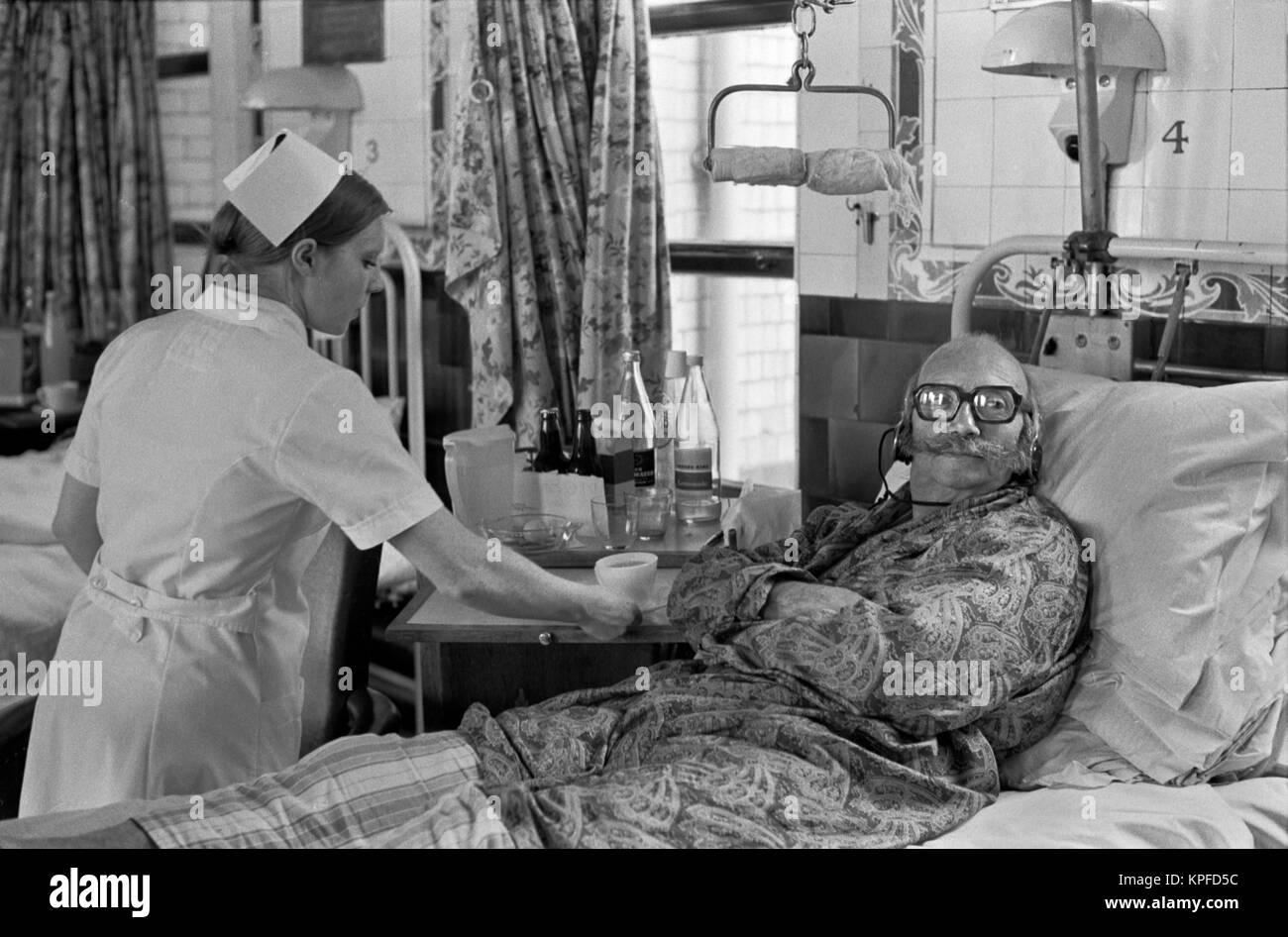 1970 NHS Charing Cross Hospital London Krankenschwester, Patient eine Tasse Tee. Hören und Sehen Tv mit Kopfhörern so leise in Bezirk England HOMER 1972 SYKES Stockfoto