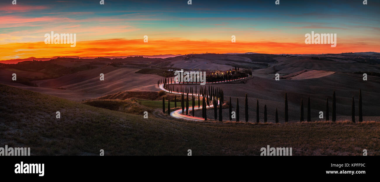 Toskana, Sonnenuntergang Landschaft im ländlichen Raum. Landschaft Bauernhof, Zypressen Bäume, grüne Wiese, Sonnenlicht und Cloud. Italien, Europa. Stockfoto