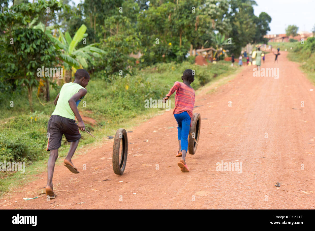 Lugazi, Uganda. 15. Juni 2017. Ugandische Kinder laufen und Spinning Rad Reifen. Stockfoto