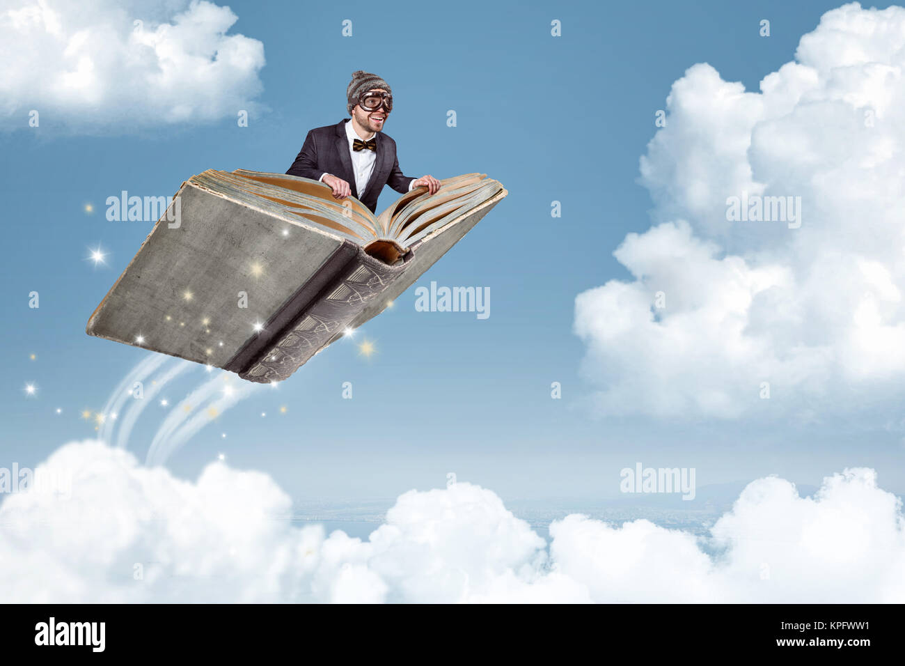 Mann Fliegen an einem Buch über den Wolken Stockfoto