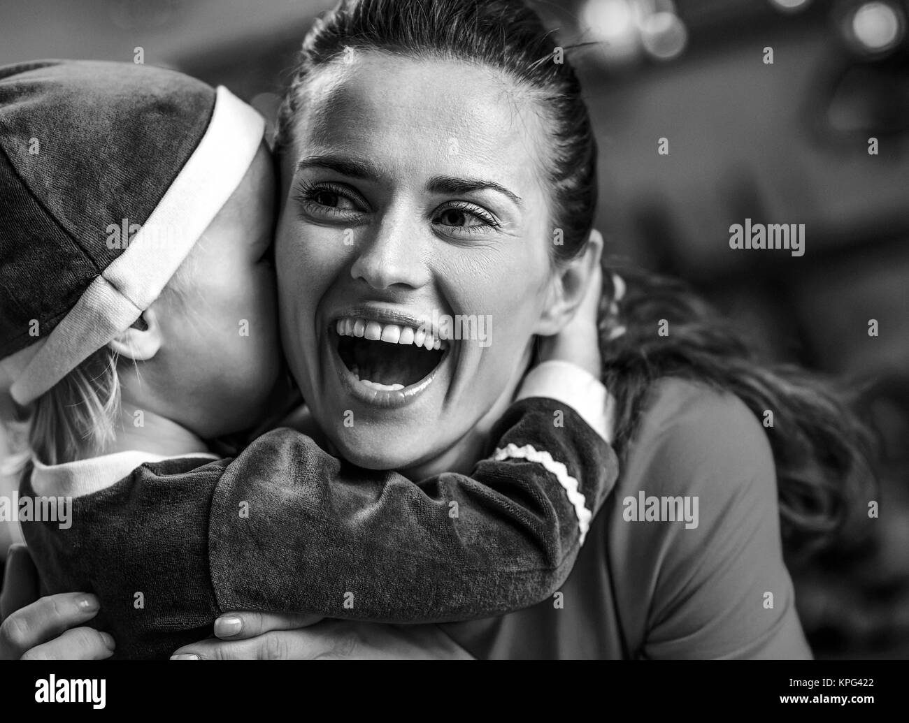 Baby-glückliche Mutter umarmt und Weihnachten eingerichtet Küche Stockfoto