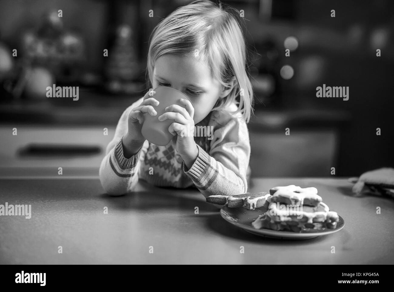Baby trinken Milch mit Weihnachtsgebäck in Küche Stockfoto