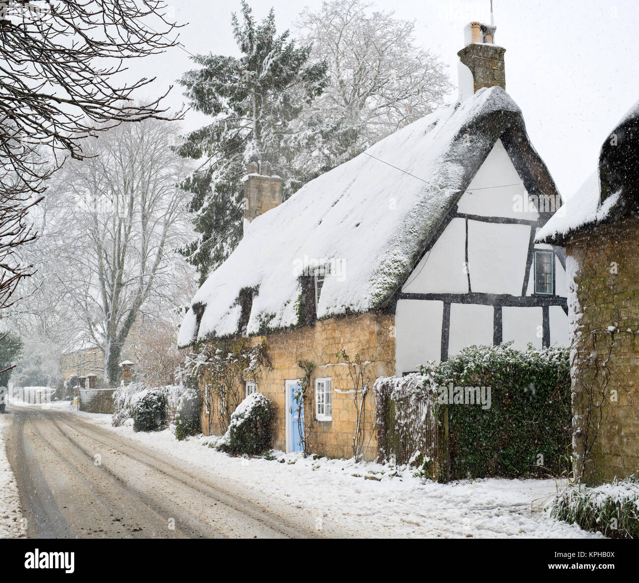 Schneebedeckte reetgedeckte Hütten am Broadway im Dezember. Broadway, Cotswolds, Worcestershire, England Stockfoto