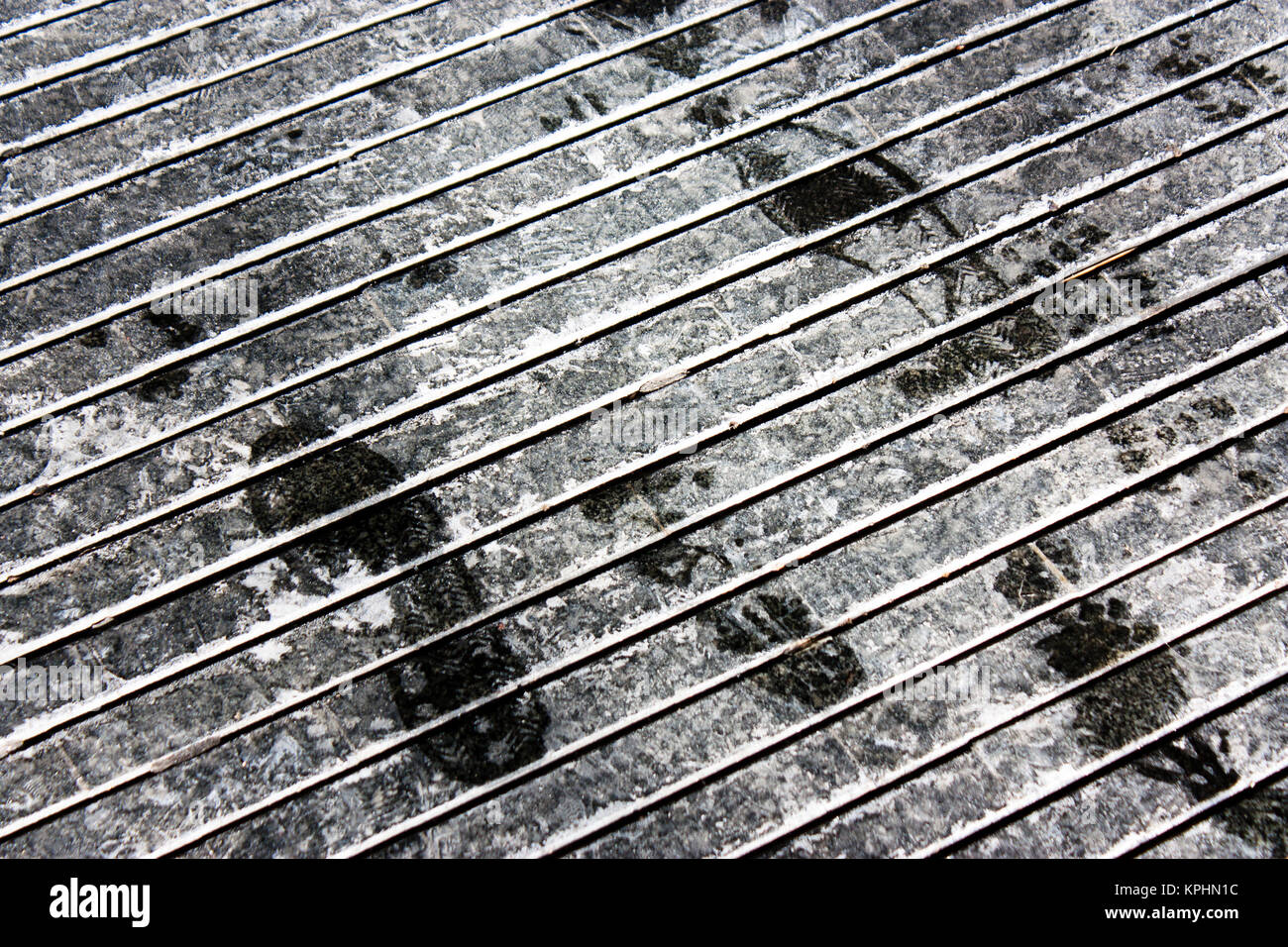 Nasse Schuh druckt auf trockenen Rutschfestes Muster bürgersteig mit Streusalz weiße Markierungen im Winter in Schwarz und Weiß Stockfoto