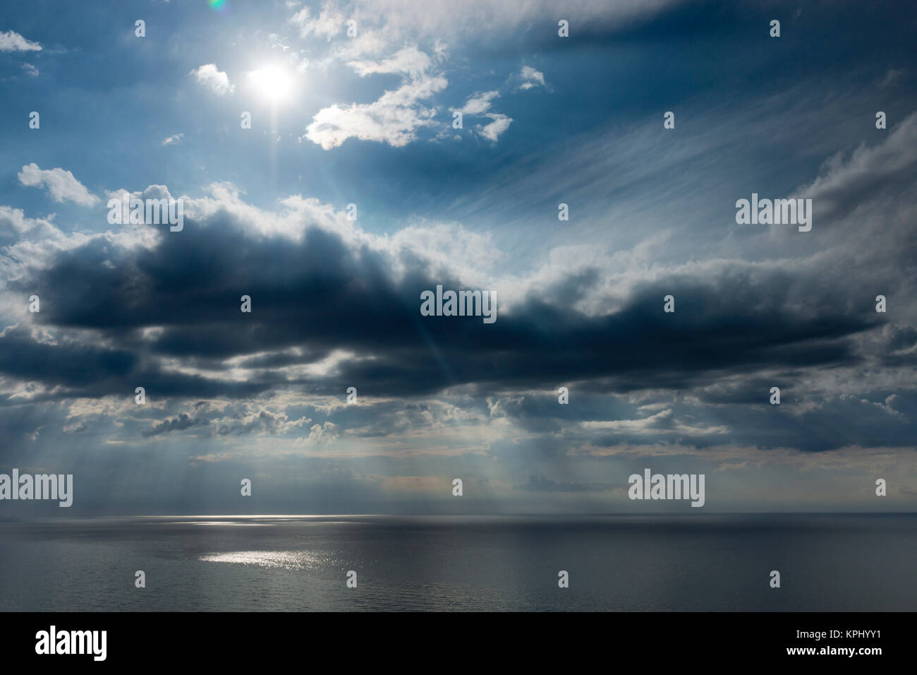 Ostsee im Sommer mit Sonne im Gegenlicht und Reflectionen, Untergehende Sonne bestrahlt Äste und Steine im Meerwasser Stockfoto