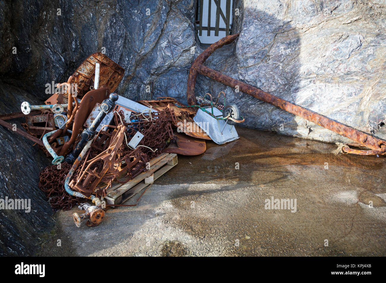 Rostiger Anker, Ketten und andere Elemente in einer felsigen Bucht in Mevagissey Cornwall. Stockfoto