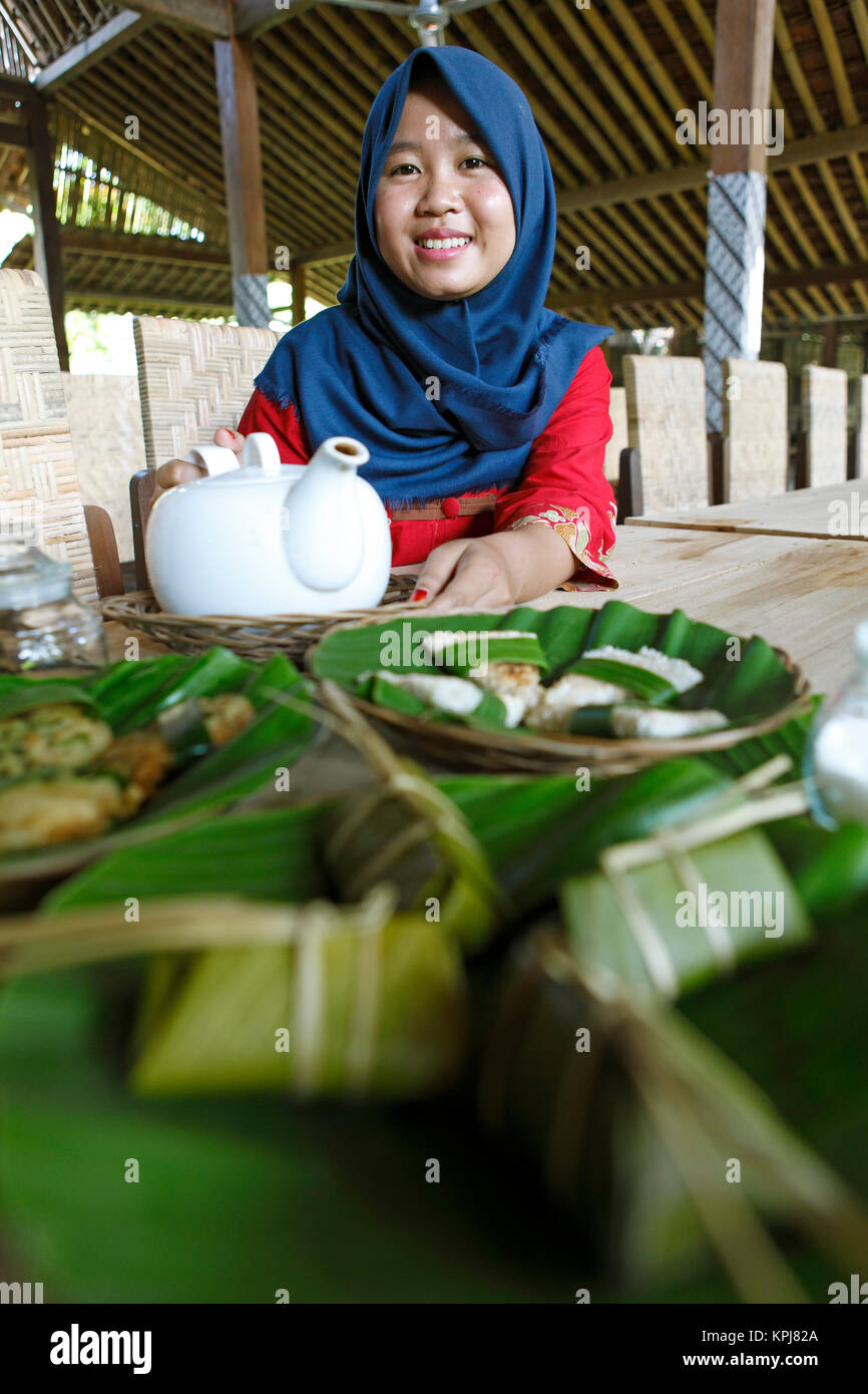 Muslimische Frau, 20 Jahre alt, serviert Tee und Javanischen Vorspeisen, Cadirejo Dorf, Magelang, Java, Indonesien Stockfoto