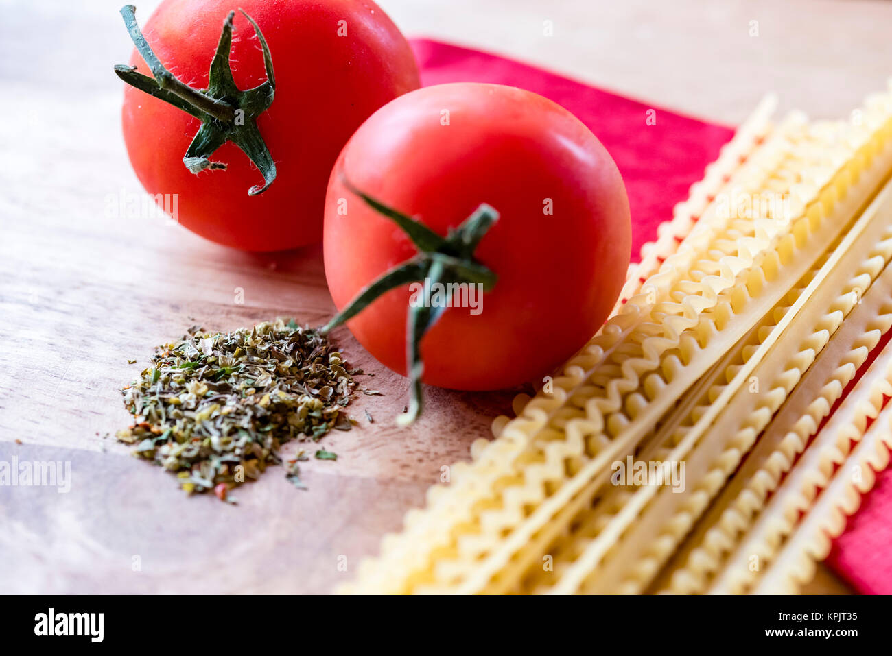 Trockene Spaghetti, frische Tomaten und italienische Kräuter, Nahaufnahme, hohen Winkel. Zutaten für italienische Pasta essen, rot Serviette, Holz- Hintergrund. Stockfoto