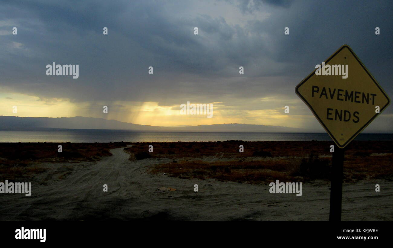 Einsame Straße Schild, auf dem Bürgersteig Enden punkte Piste in dunklen Wolken mit Regen in der Wüste in der Salton Sea Stockfoto