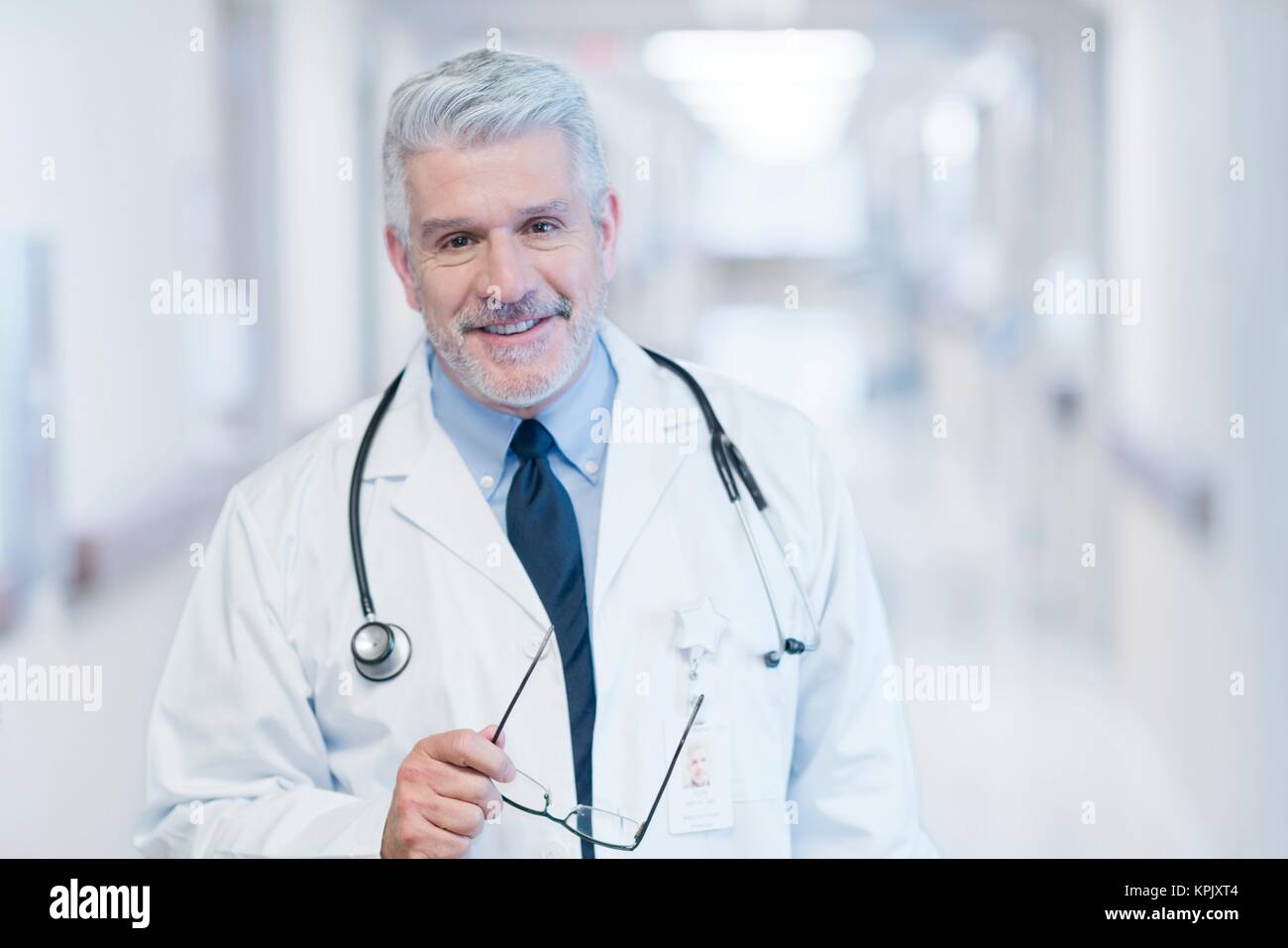Reife männliche Arzt in Richtung Kamera lächelnd. Stockfoto