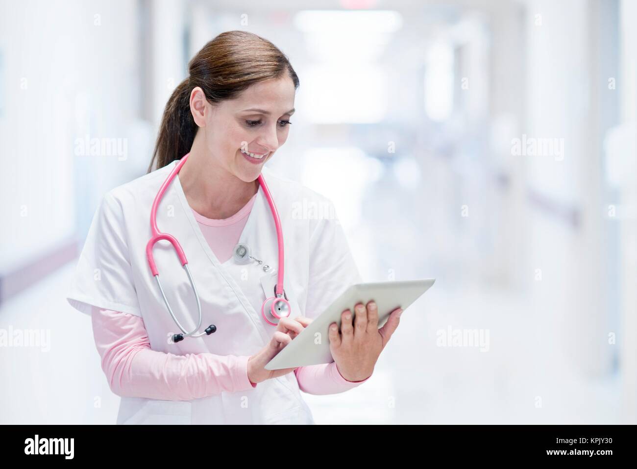 Krankenschwester im Krankenhaus mit digitalen Tablet, lächelnd. Stockfoto