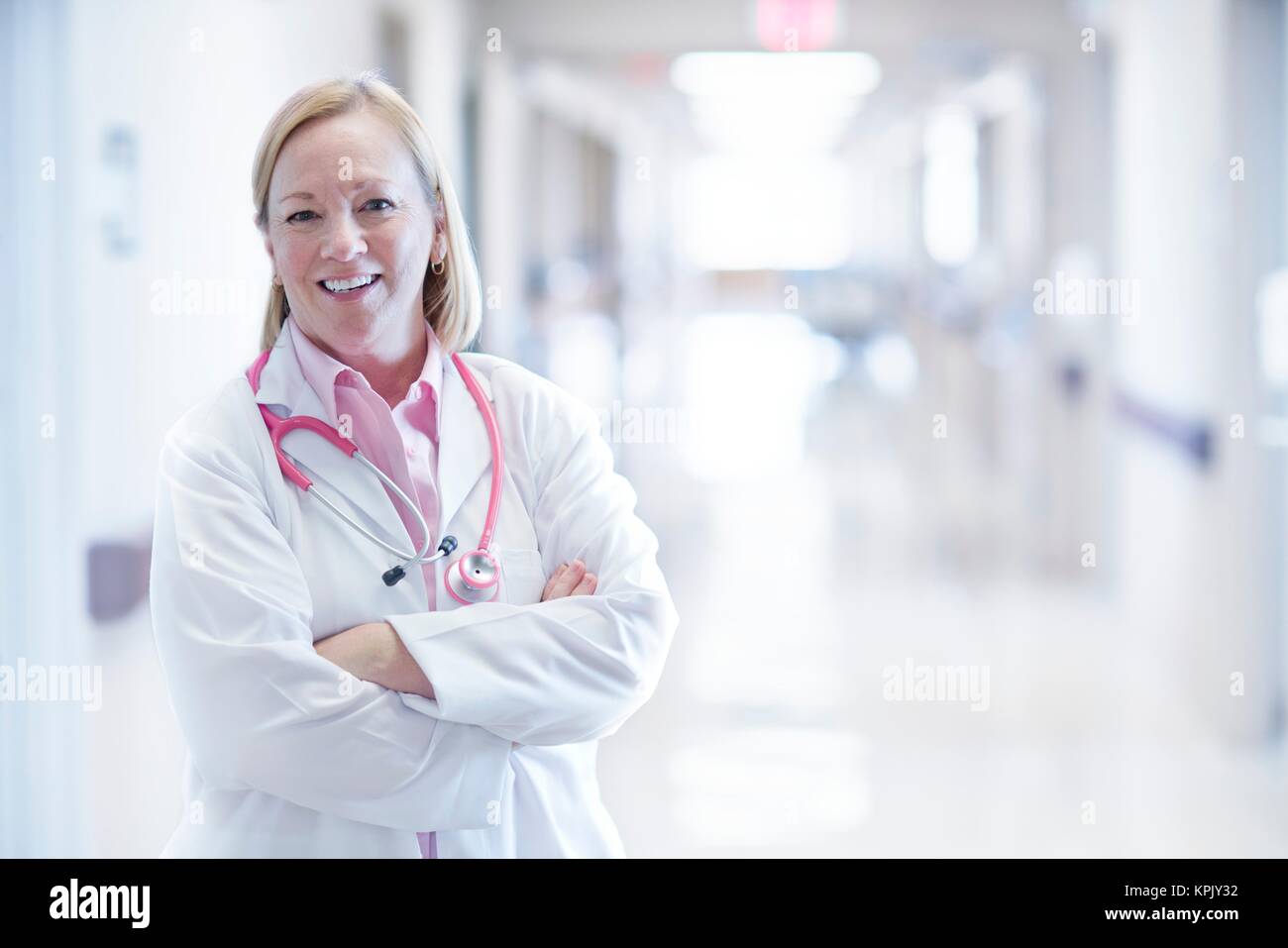 Reife Krankenschwester lächelnd mit verschränkten Armen, Portrait. Stockfoto