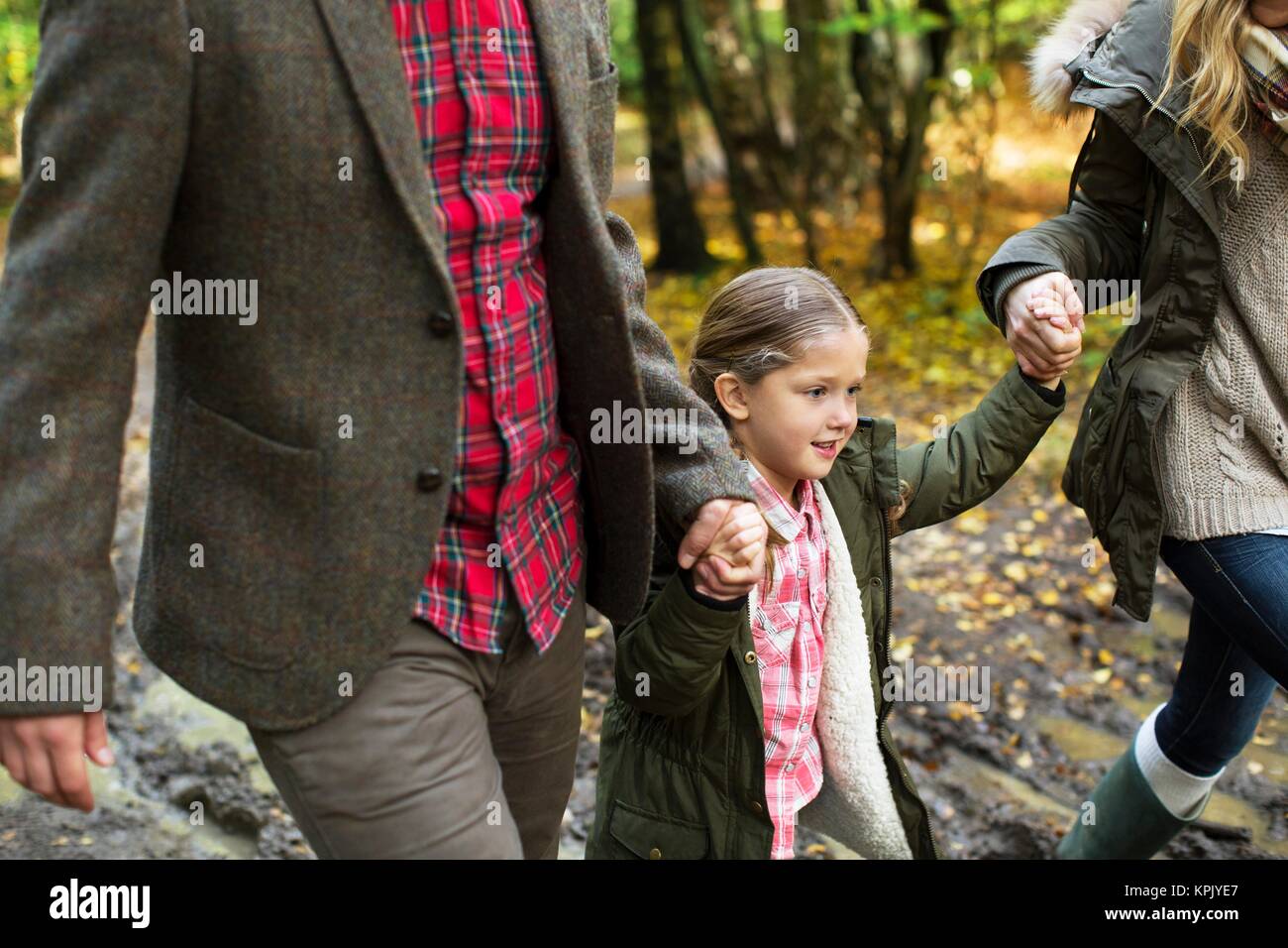 Junge Mädchen auf einem Spaziergang Hand in Hand mit ihren Eltern. Stockfoto