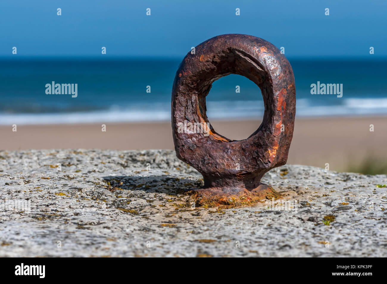 Rusty Ring auf einem Felsen an der Küste entlang mit einem Strand im Hintergrund; South Shields, Tyne und Wear, England Stockfoto